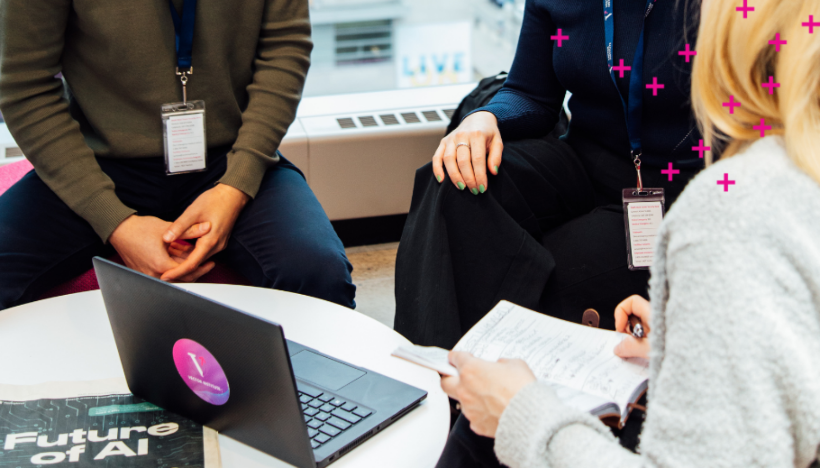 Three people surrounding a laptop with a Vector Institute sticker on it