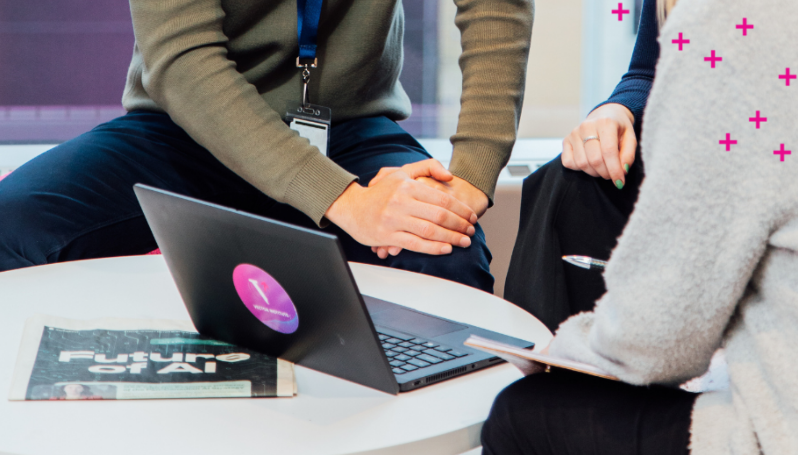 Three people stare at a laptop with a Vector logo on it