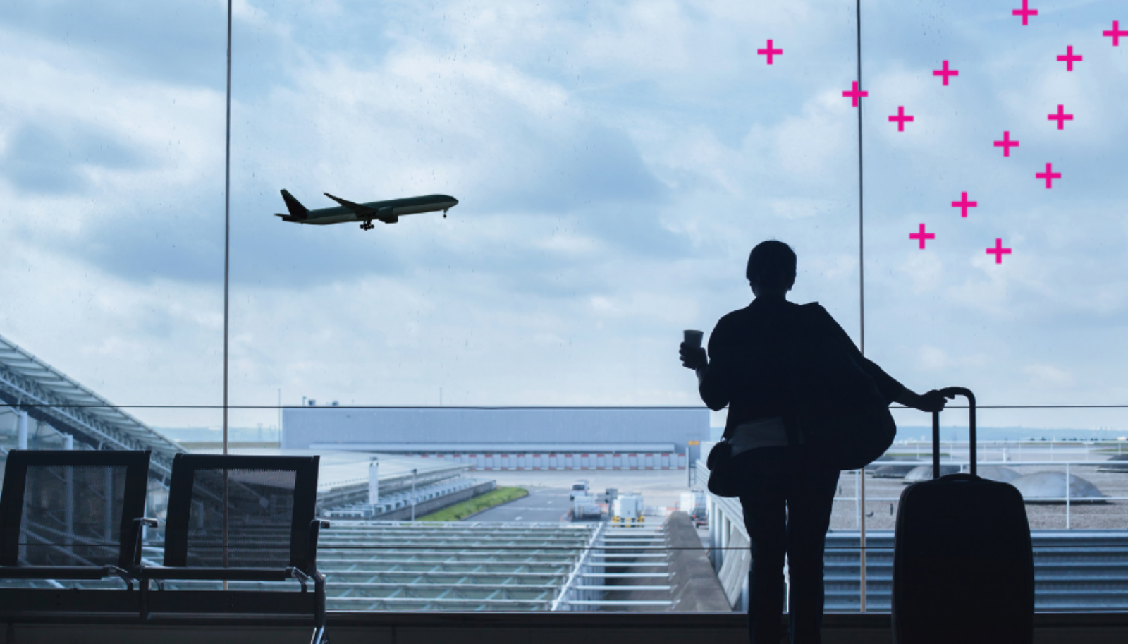 Women holding a suitcase looks out the window at a plane flying by